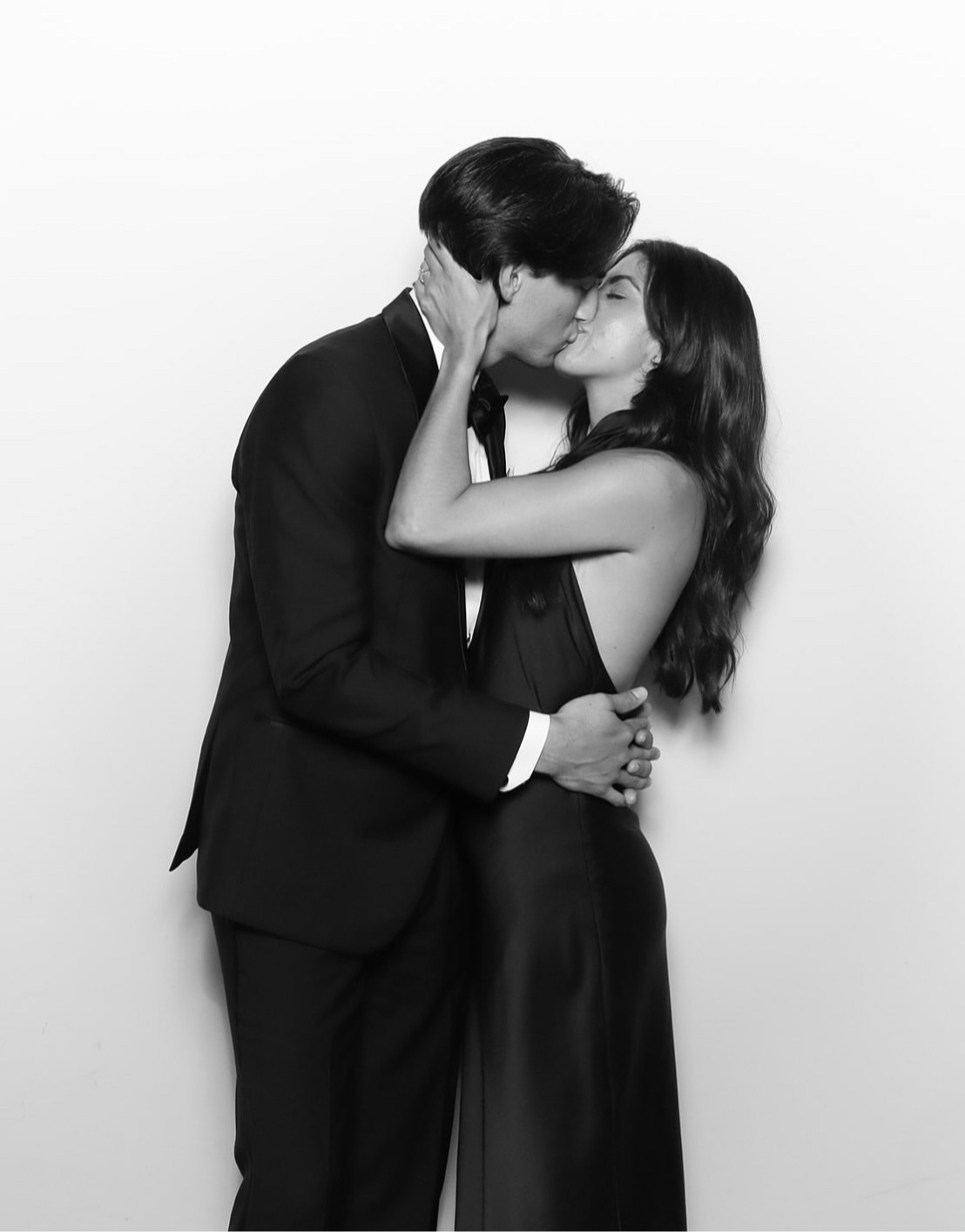 Black and white photo of a couple embracing against a plain background