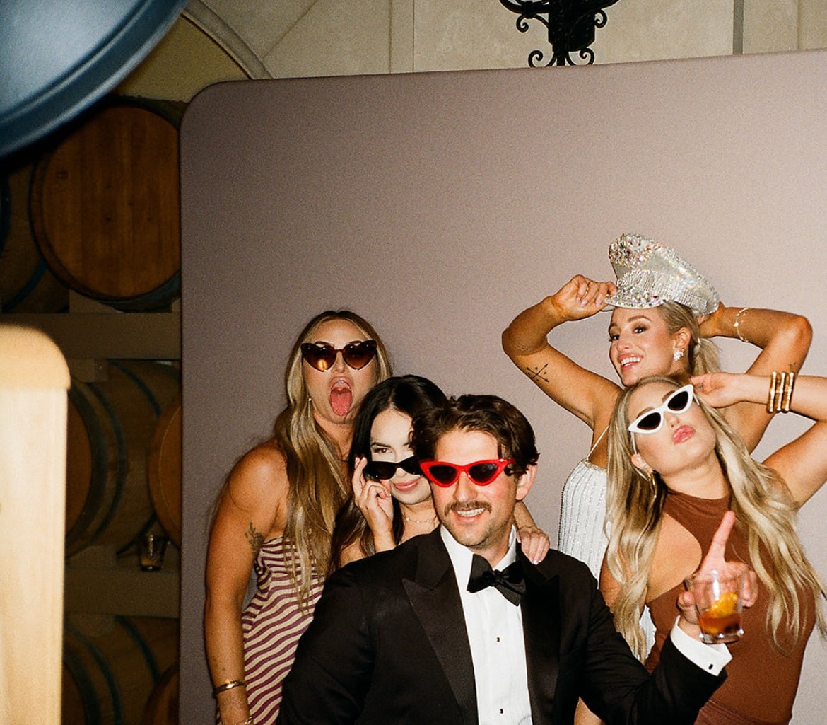 Group of people posing for a photo in a formal setting with one person in a tuxedo.