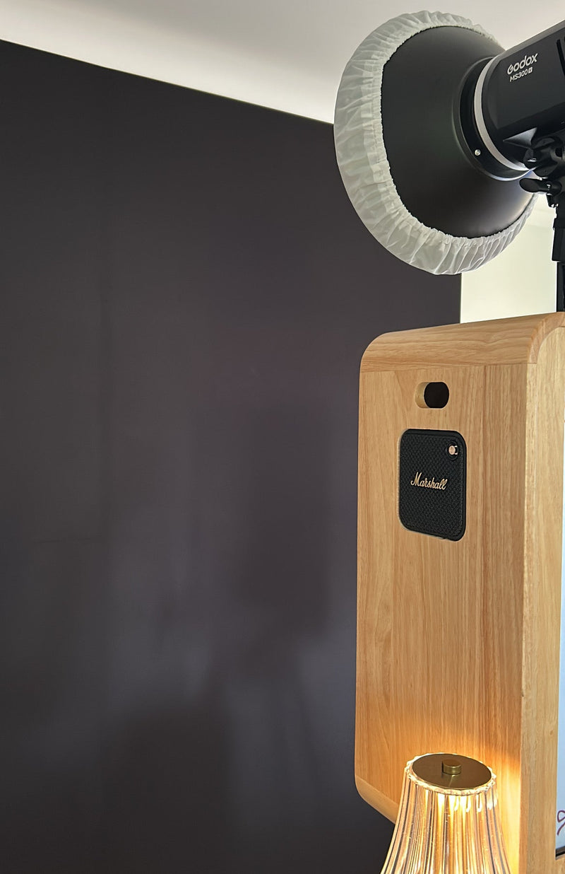 Wooden speaker with Marshall logo and a camera on top against a dark background