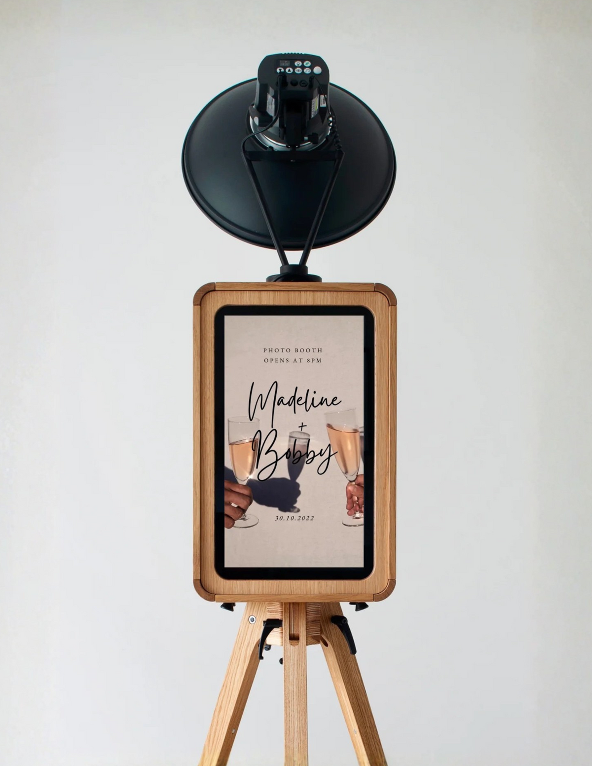 Photo booth with wooden frame and black camera on a white background