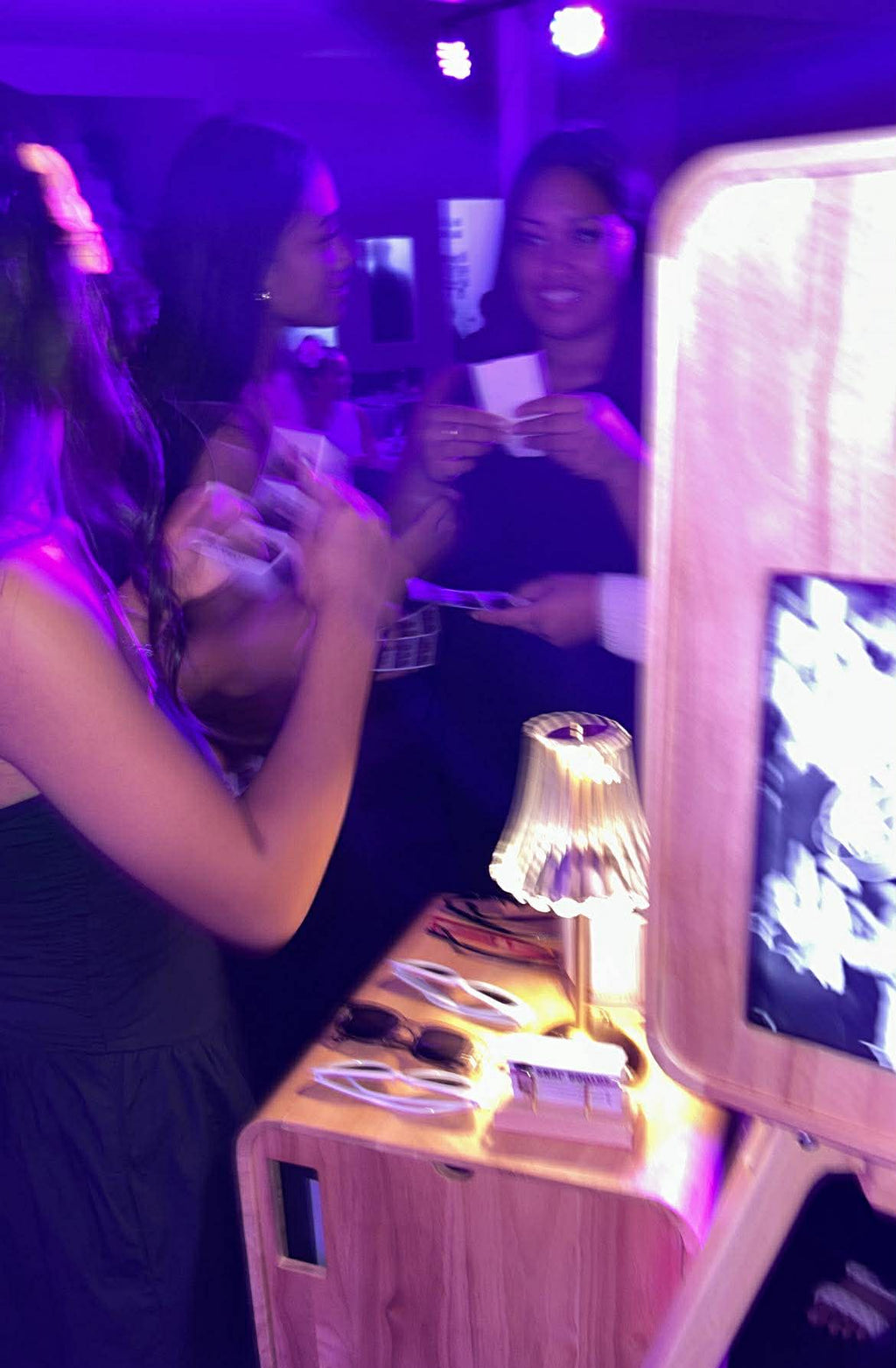 People at a party with a wooden photo booth and lamp.