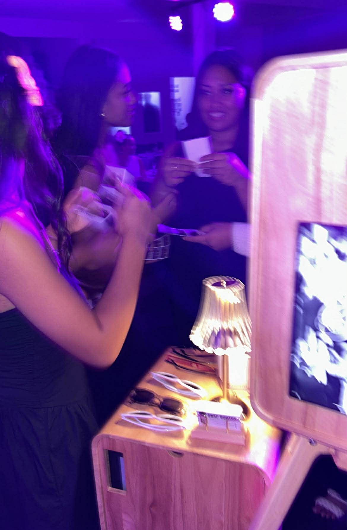 People at a party with a wooden photo booth and lamp.