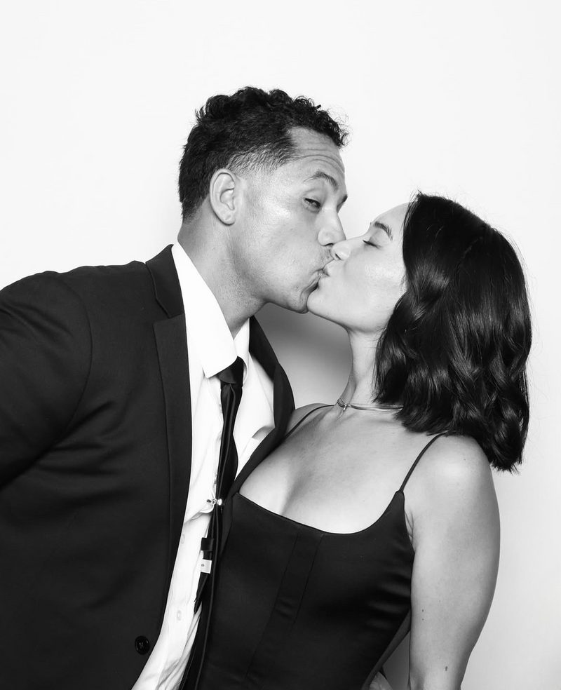 Black and white photo of a couple posing closely against a plain background